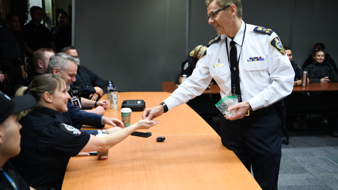 Chief Lipinski hands over badge to officer in conference room