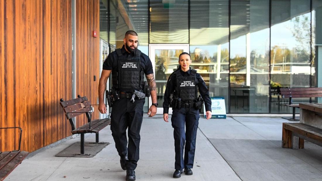 Two Surrey Police Officers in Uniform walking in front of building 